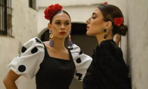mujeres con trajes de flamenca y flojor roja en la cabeza