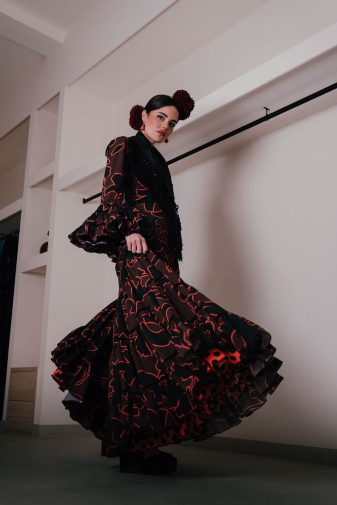 mujer vestida de flamenca con traje largo negro con estampado en tonos rojos